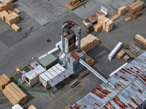 Melbourne VIC Australia 25 September 2026 Aerial view of an industrial wood processing facility with stacks of lumber rusted metal roofs and machinery in a concrete yard.