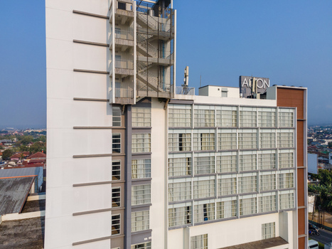 Aerial view of the modern Aston Hotel building with its glass facade and external staircase under a clear blue sky in Purwokerto Central Java Indonesia. Aerial view of the modern Aston Hotel building with its glass facade and external staircase under a clear blue sky in Purwokerto Central Java Indonesia.