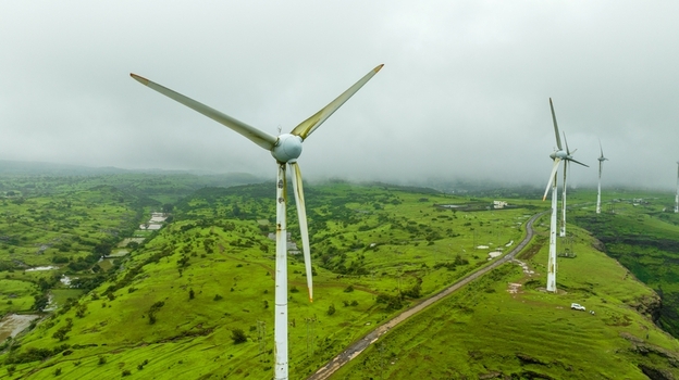 Aerial view of wind turbines standing on lush green hills in the misty landscape of Igatpuri Maharashtra India. Aerial view of wind turbines standing on lush green hills in the misty landscape of Igatpuri Maharashtra India.