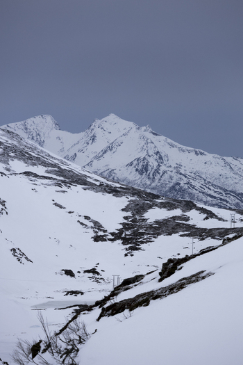 View of snowy mountain peaks and rugged arctic terrain under a moody overcast sky Kvaloya Troms Norway.