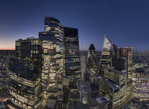 Aerial view of the City of London financial district skyscrapers including the Gherkin and Leadenhall Building with illuminated windows at twilight London England United Kingdom.