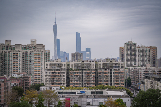 Aerial view of the Guangzhou skyline featuring the iconic Canton Tower rising above dense residential high rise buildings under a cloudy sky in Guangzhou Guangdong Province China. Aerial view of the Guangzhou skyline featuring the iconic Canton Tower rising above dense residential high rise buildings under a cloudy sky in Guangzhou Guangdong Province China.