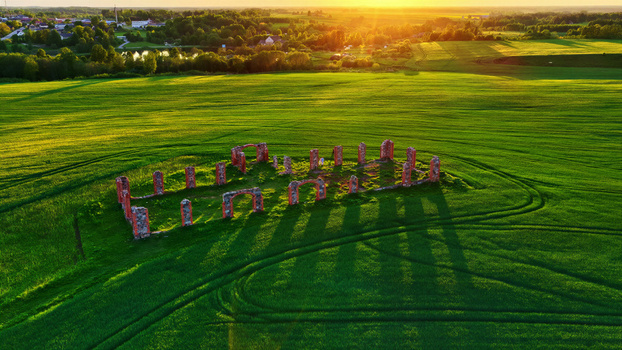 Aerial view of ancient stone ruins standing in a lush green field during golden hour in Latvia. Aerial view of ancient stone ruins standing in a lush green field during golden hour in Latvia.