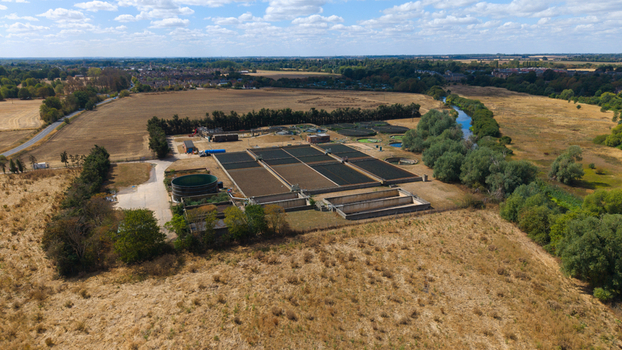 Aerial view of the wastewater treatment works facility featuring settling tanks filtration beds and surrounding rural landscape with a river and trees in St Neots England United Kingdom. Aerial view of the wastewater treatment works facility featuring settling tanks filtration beds and surrounding rural landscape with a river and trees in St Neots England United Kingdom.