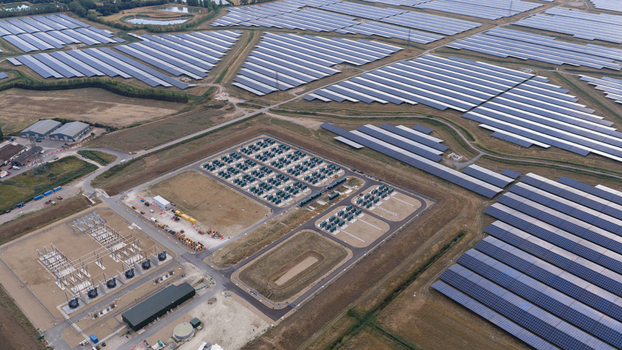 Aerial view of a large scale solar farm featuring extensive rows of photovoltaic panels battery energy storage systems and electrical substation infrastructure in London England United Kingdom.