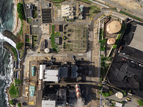 Aerial view of the industrial power plant with storage tanks a smokestack and coal piles along the coastline in Bajos de Haina San Cristobal Province Dominican Republic.
