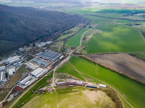 Aerial view of industrial buildings nestled between verdant fields and a dense forest where the stark lines of man made structures meet the rolling hills Detva Banskobystricky kraj Slovakia. Aerial view of industrial buildings nestled between verdant fields and a dense forest where the stark lines of man made structures meet the rolling hills Detva Banskobystricky kraj Slovakia.