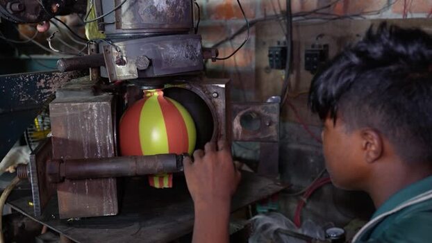 View of a worker operating a balloon molding machine Bangladesh. View of a worker operating a balloon molding machine Bangladesh.