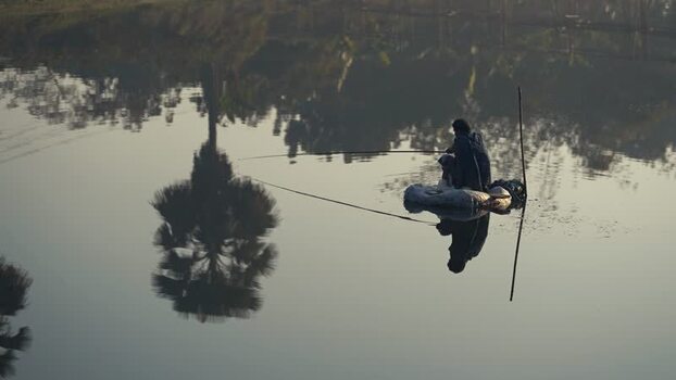View of a fisherman on a small boat in a calm river Bangladesh. View of a fisherman on a small boat in a calm river Bangladesh.