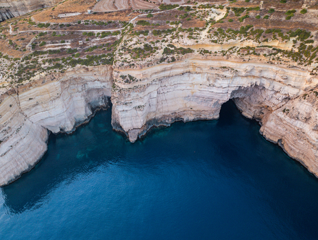 Aerial view of dramatic Sanap Cliffs plunging into the deep blue sea creating a striking contrast of textures and tones Munxar Gozo Malta. Aerial view of dramatic Sanap Cliffs plunging into the deep blue sea creating a striking contrast of textures and tones Munxar Gozo Malta.