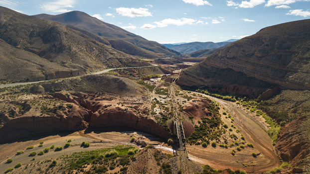 Aerial view of a rugged arid landscape with a dry riverbed a railway bridge and surrounding mountains under a clear blue sky in Argentina. Aerial view of a rugged arid landscape with a dry riverbed a railway bridge and surrounding mountains under a clear blue sky in Argentina.
