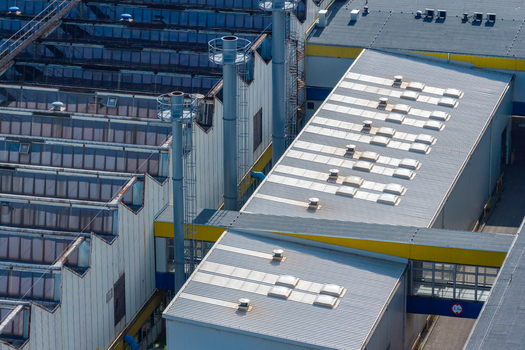 Aerial view of an agricultural machinery production facility with industrial rooftops skylights and tall ventilation chimneys in Plock Mazowieckie Poland. Aerial view of an agricultural machinery production facility with industrial rooftops skylights and tall ventilation chimneys in Plock Mazowieckie Poland.