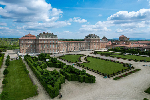 Aerial view of La Venaria Reale palace featuring formal gardens with manicured hedges and historic architecture under a blue sky in Venaria Reale Piemonte Italy. Aerial view of La Venaria Reale palace featuring formal gardens with manicured hedges and historic architecture under a blue sky in Venaria Reale Piemonte Italy.
