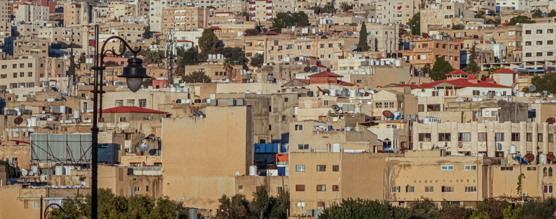View of the dense urban landscape of Jerash featuring residential buildings rooftops with water tanks and a street lamp in the foreground in Jerash Jerash Governorate Jordan. View of the dense urban landscape of Jerash featuring residential buildings rooftops with water tanks and a street lamp in the foreground in Jerash Jerash Governorate Jordan.
