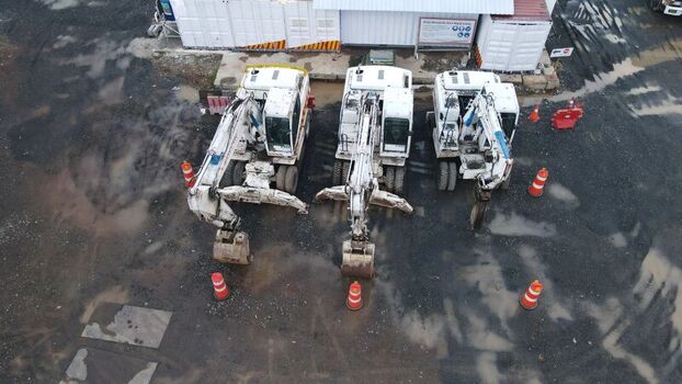 Aerial view of three white excavators parked in a row on a muddy construction site at Bambu Apus in Kecamatan Cipayung Daerah Khusus Ibukota Indonesia. Aerial view of three white excavators parked in a row on a muddy construction site at Bambu Apus in Kecamatan Cipayung Daerah Khusus Ibukota Indonesia.