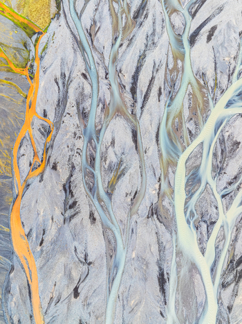 Aerial view of a complex braided river system with glacial water flowing through dark sediment and vibrant mineral deposits in Iceland. Aerial view of a complex braided river system with glacial water flowing through dark sediment and vibrant mineral deposits in Iceland.
