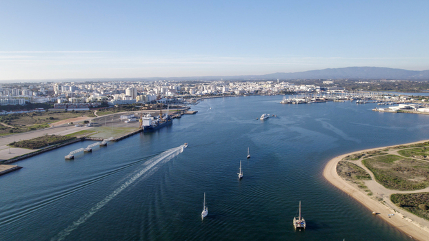 Aerial view of the Arade River estuary with sailboats and a motorboat featuring the urban skyline of Ferragudo and Portimao in the background Ferragudo Faro District Portugal.