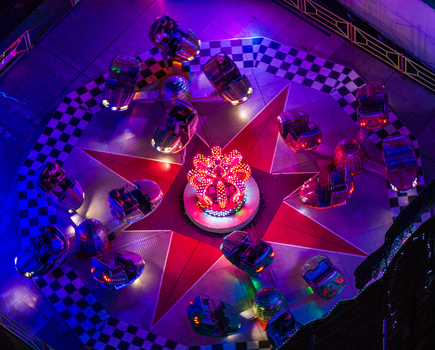 Aerial view of a colorful fairground ride illuminated with bright lights at night featuring spinning cars on a star shaped platform in Vilnius Vilnius County Lithuania. Aerial view of a colorful fairground ride illuminated with bright lights at night featuring spinning cars on a star shaped platform in Vilnius Vilnius County Lithuania.