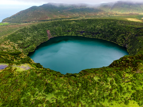 Aerial view of a vibrant turquoise lake nestled within the lush green crater of a volcanic landscape Flores Azores Portugal.