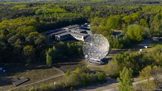 Aerial view of the Dwingeloo Radio Observatory with its large parabolic dish antenna surrounded by lush green forests and research facilities Dwingeloo Drenthe Netherlands.