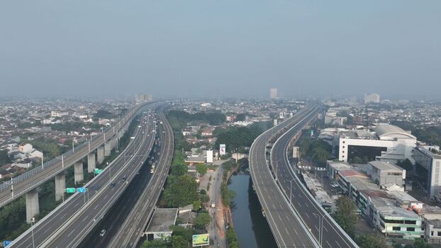 Aerial view of the elevated highway and railway tracks winding through the dense urban landscape of Bekasi Barat West Java Indonesia. Aerial view of the elevated highway and railway tracks winding through the dense urban landscape of Bekasi Barat West Java Indonesia.
