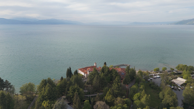 Aerial view of Saint Naum Monastery situated on the shore of Lake Ohrid surrounded by lush trees and calm waters with mountains in the distance Municipality of Ohrid North Macedonia.