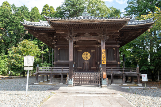 View of an old wooden temple standing peacefully among lush trees with intricate carvings and a golden emblem reflecting serenity and heritage Narita Chiba Japan. View of an old wooden temple standing peacefully among lush trees with intricate carvings and a golden emblem reflecting serenity and heritage Narita Chiba Japan.