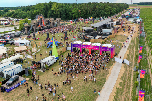 Herzogenaurach Germany 24 July 2025 Aerial view of the Open Beatz Festival featuring large stages crowds of people and festival infrastructure surrounded by lush green trees.
