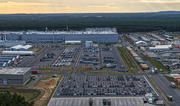 Aerial view of Tesla Gigafactory Berlin Brandenburg showing the manufacturing facility parking lots filled with new cars and surrounding forest in Grunheide Mark Brandenburg Germany. Aerial view of Tesla Gigafactory Berlin Brandenburg showing the manufacturing facility parking lots filled with new cars and surrounding forest in Grunheide Mark Brandenburg Germany.