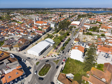 Aerial view of a vibrant cityscape with terracotta roofs a prominent white event tent and a serene river in the distance Ilhavo Aveiro Portugal. Aerial view of a vibrant cityscape with terracotta roofs a prominent white event tent and a serene river in the distance Ilhavo Aveiro Portugal.