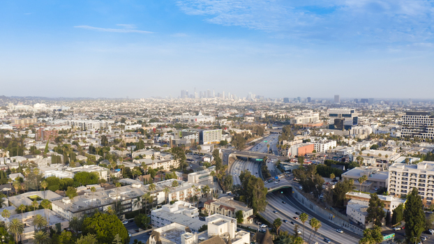 Aerial view of the Los Angeles cityscape featuring a busy highway cutting through urban neighborhoods office buildings and residential areas in Los Angeles California United States.