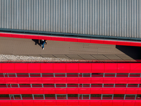 Aerial view of a person sitting on the wooden terrace of a modern building with a vibrant red facade in Belgrade City of Belgrade Serbia. Aerial view of a person sitting on the wooden terrace of a modern building with a vibrant red facade in Belgrade City of Belgrade Serbia.