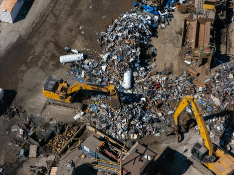 Aerial view of excavators sorting through large piles of scrap metal at a recycling facility in Carson California United States.
