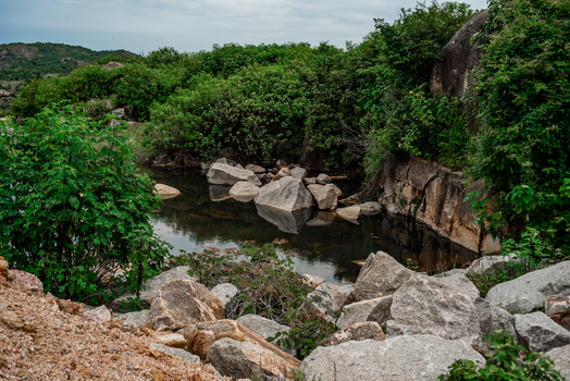 View of a tranquil pond surrounded by large granite boulders and lush green vegetation in the rocky landscape of Jos North Plateau Nigeria. View of a tranquil pond surrounded by large granite boulders and lush green vegetation in the rocky landscape of Jos North Plateau Nigeria.