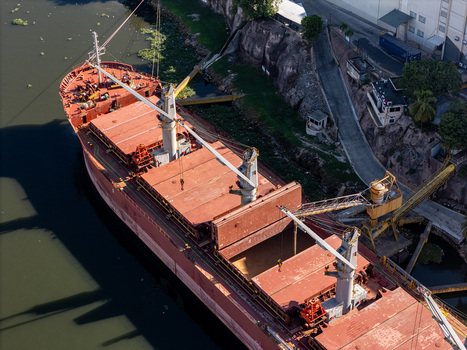 Aerial view of a large red cargo ship docked on the Rio Ozama with cranes and industrial infrastructure in Santo Domingo Santo Domingo Dominican Republic.