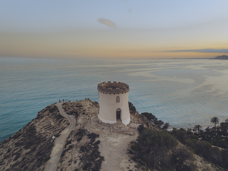 Aerial view of the Santuari iber i roma de la Malladeta tower on a rocky cliff overlooking the Mediterranean Sea at sunset in La Vila Joiosa Comunidad Valenciana Spain. Aerial view of the Santuari iber i roma de la Malladeta tower on a rocky cliff overlooking the Mediterranean Sea at sunset in La Vila Joiosa Comunidad Valenciana Spain.