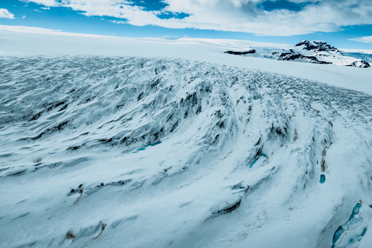 Aerial view of Vatnajokull glacier with deep blue crevasses and vast snowfields in Iceland.