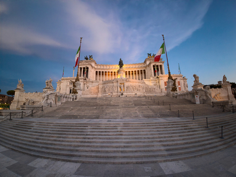 View of the Monument to Victor Emmanuel II with its grand white marble staircase and Italian flags under a clear blue sky in Roma Lazio Italy.
