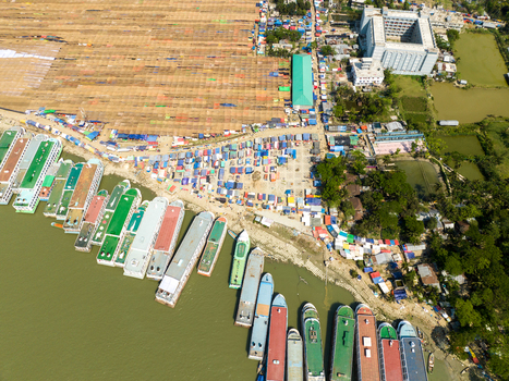 Aerial view of boats lining the river s edge contrasting with the bustling marketplace and the tranquil green fields Charmonai Barisal Division Bangladesh. Aerial view of boats lining the river s edge contrasting with the bustling marketplace and the tranquil green fields Charmonai Barisal Division Bangladesh.