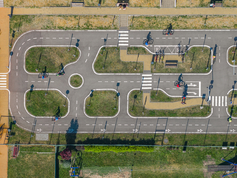 Aerial view of a children s traffic playground with people cycling on paved paths featuring road markings and crosswalks in Kyjov South Moravian Region Czechia.