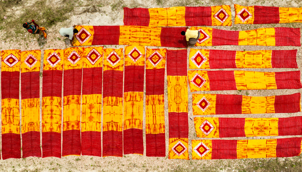 Narayanganj Bangladesh 30 March 2026 Aerial view of vibrant red and yellow fabrics stretched out in geometric patterns contrasting against the sandy backdrop.