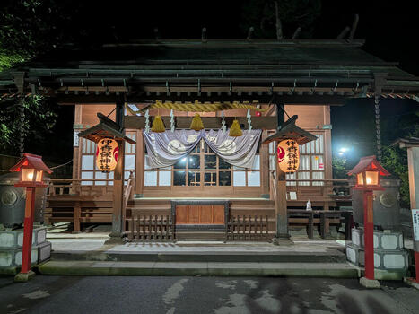 View of the illuminated Ikaho Shrine at night featuring traditional wooden architecture hanging lanterns and a decorative curtain located in Shibukawa Gunma Japan.