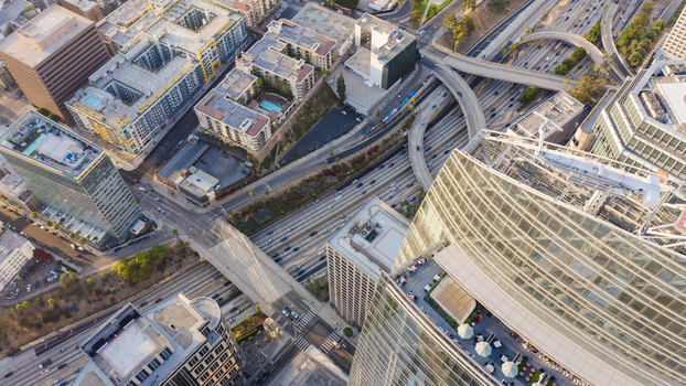 Aerial view of the dense urban landscape featuring modern skyscrapers complex highway interchanges and busy traffic in Los Angeles California United States.