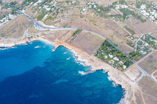 Aerial view of the Riserva Naturale Orientata dello Zingaro coastline with turquoise sea rugged cliffs winding road and Mediterranean vegetation in San Vito Lo Capo Sicilia Italy. Aerial view of the Riserva Naturale Orientata dello Zingaro coastline with turquoise sea rugged cliffs winding road and Mediterranean vegetation in San Vito Lo Capo Sicilia Italy.