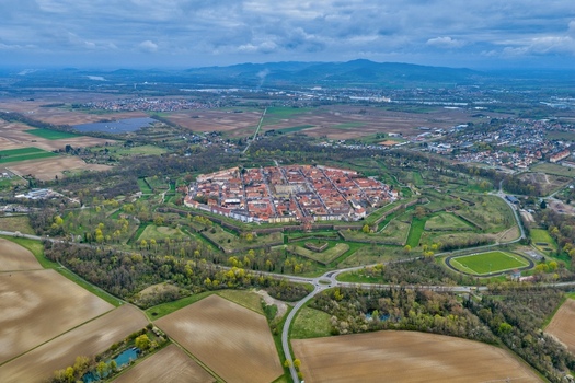 Aerial view of the octagonal fortress city a starburst of red tiled roofs and green ramparts contrasting against the flat cultivated fields under a vast sky Neuf Brisach Grand Est France.