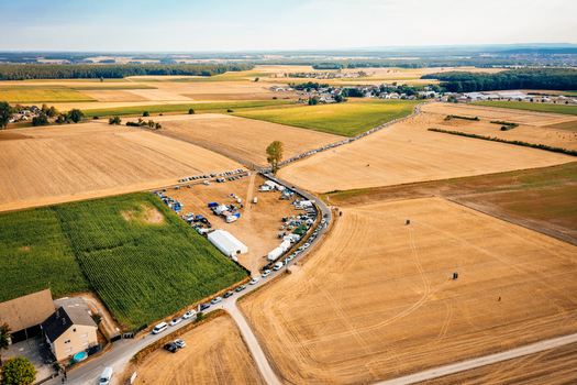 Aerial view of Open Beatz Festival site with tents and parked cars surrounded by golden agricultural fields and rural landscapes Herzogenaurach Bayern Germany. Aerial view of Open Beatz Festival site with tents and parked cars surrounded by golden agricultural fields and rural landscapes Herzogenaurach Bayern Germany.