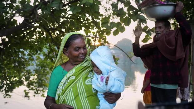 View of a woman holding a baby by a river in Bogura Bangladesh. View of a woman holding a baby by a river in Bogura Bangladesh.