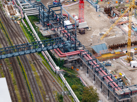 Aerial view of Heizkraftwerk Reuter West power plant undergoing conversion with industrial piping railway tracks and construction equipment in Berlin Berlin Germany.