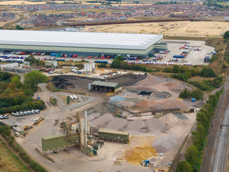 Aerial view of Tarmac Elstow Asphalt facility with piles of gravel industrial machinery and a large warehouse in the background in Elstow England United Kingdom. Aerial view of Tarmac Elstow Asphalt facility with piles of gravel industrial machinery and a large warehouse in the background in Elstow England United Kingdom.