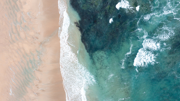 Aerial view of the sandy shoreline and turquoise ocean waves at Constantine Bay in Padstow Cornwall United Kingdom. Aerial view of the sandy shoreline and turquoise ocean waves at Constantine Bay in Padstow Cornwall United Kingdom.